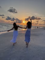 Two girls frolicking on a beach in the sunset